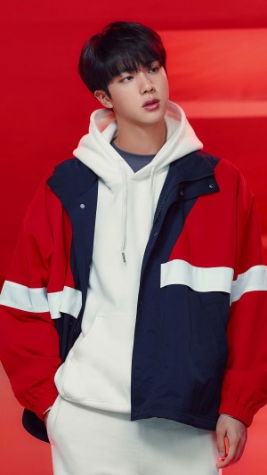Jin from BTS in a red, white, and navy jacket