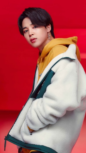 Jimin from BTS wearing a yellow hoodie and white jacket