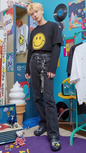Taehyun from TXT wearing a smiley face shirt