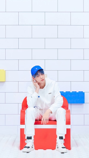 Soobin from TXT wearing a white hoodie and blue cap