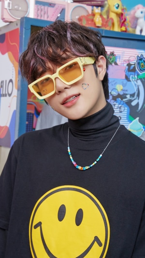 Choi Beomgyu from TXT wearing sunglasses and a smiley face t-shirt
