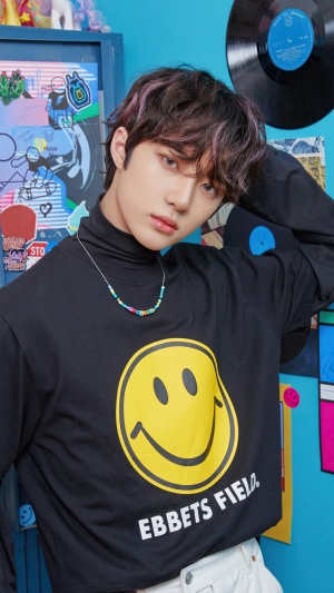 Choi Beomgyu from TXT wearing a black smiley face shirt