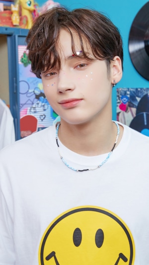 Huening Kai from TXT wearing a smiley face t-shirt