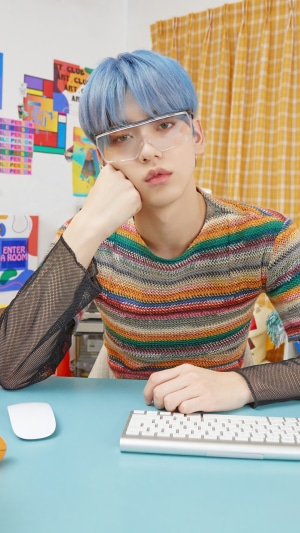 Soobin from TXT wearing glasses and a colorful sweater