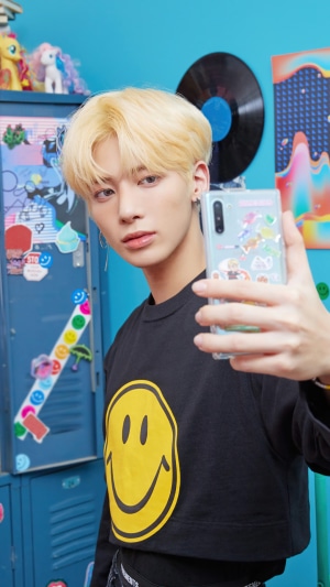 Taehyun from TXT taking a selfie with a phone
