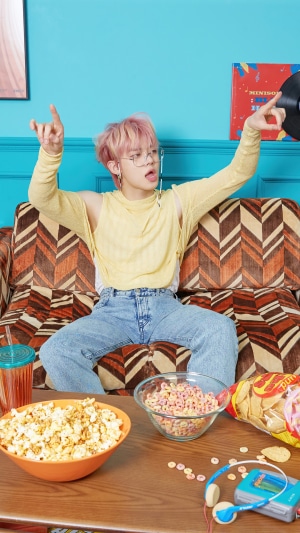 Yeonjun from TXT sitting on a couch with snacks