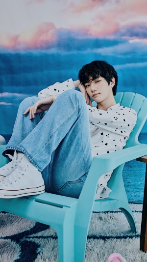 Beomgyu from TXT sitting in a chair