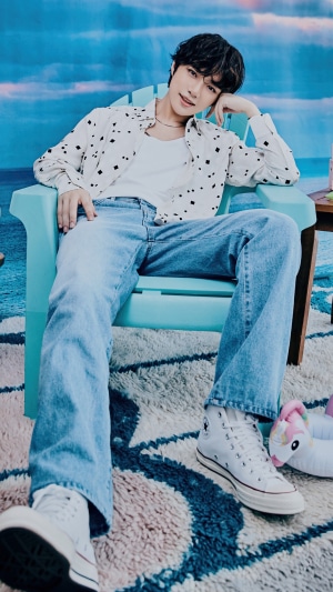 Beomgyu from TXT sitting in a chair