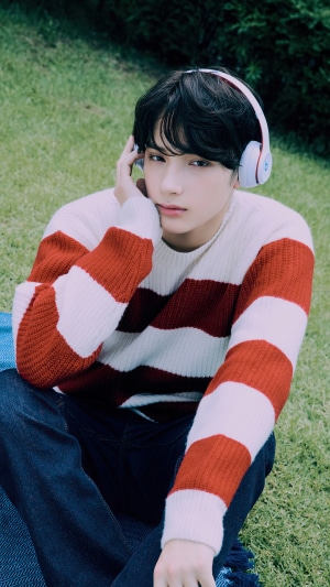 Huening Kai from TXT wearing headphones outdoors
