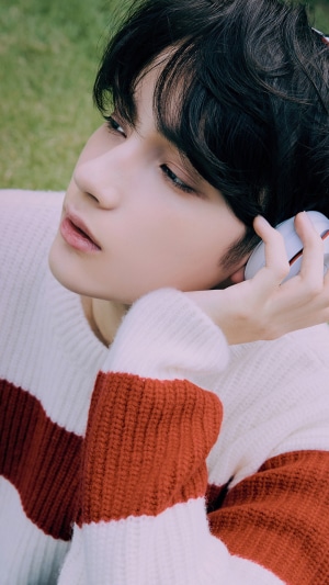 Huening Kai from TXT wearing a striped sweater