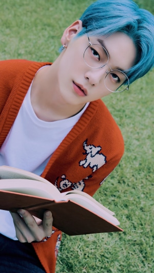 Soobin from TXT wearing glasses and holding a book