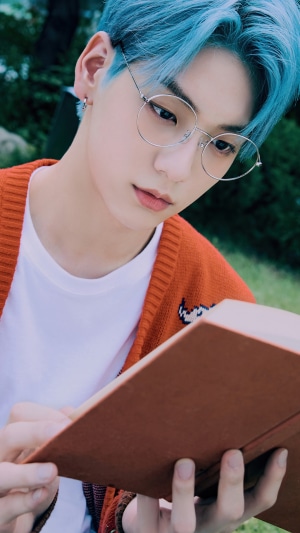 Soobin from TXT wearing glasses and reading a book