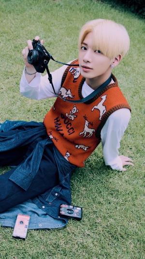 Taehyun from TXT holding a camera outdoors