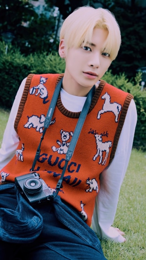 Taehyun from TXT wearing a Gucci vest with a camera