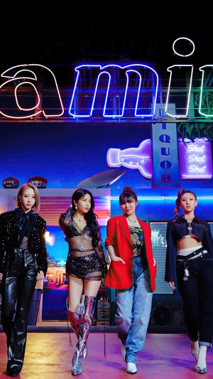 MAMAMOO members posing in front of a neon sign