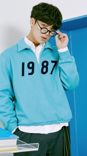 Kim Min Gyu from Seventeen wearing glasses and a blue sweatshirt