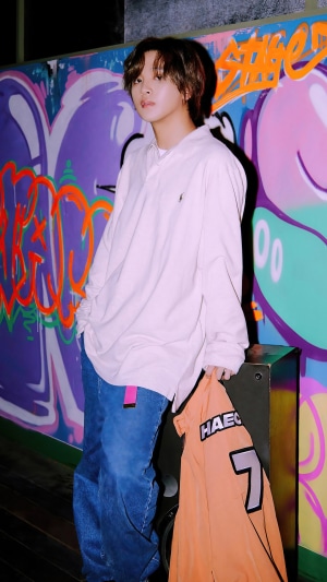 Haechan from NCT Dream posing in front of graffiti