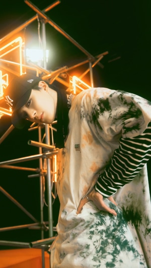 Jeno from NCT U wearing a tie-dye shirt and baseball cap