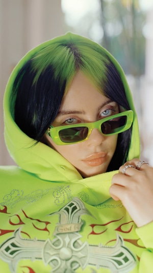 Billie Eilish wearing sunglasses and a hoodie