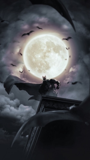 Batman sitting on a building ledge at night