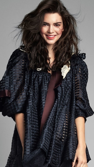 Kendall Jenner smiling in a dark outfit
