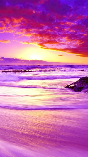 Purple and orange sunset over a beach with waves
