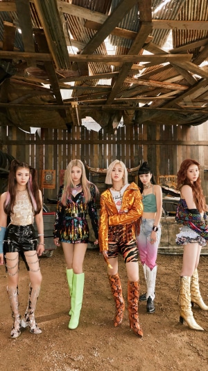 ITZY members posing in a rustic, abandoned building