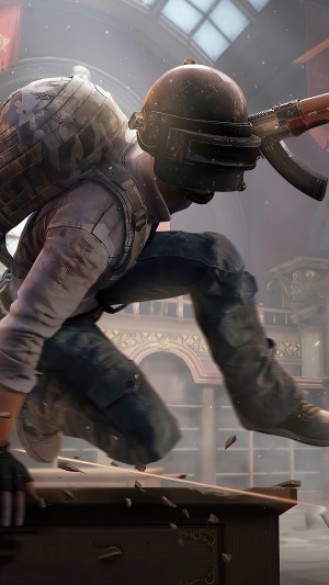 Player in PUBG helmet jumps over a table with a rifle