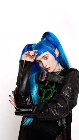 Ashnikko with blue pigtails wearing a black jacket