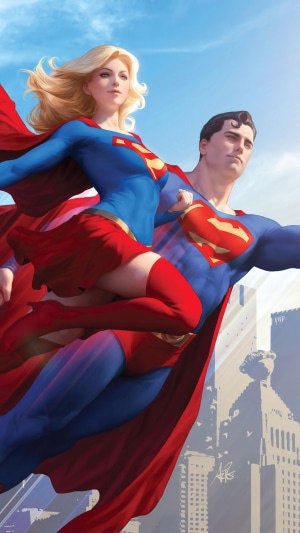 Superman and Supergirl flying over a city