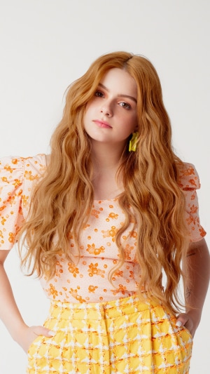 Ariel Winter posing in a floral top and yellow pants