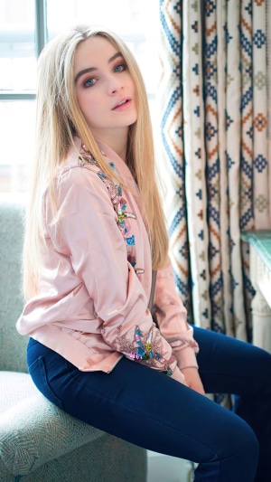 Sabrina Carpenter in a pink bomber jacket and jeans