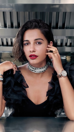 Naomi Scott wearing a black dress and jewelry