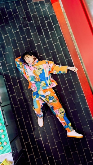 Baekhyun lying on black tiles wearing colorful outfit