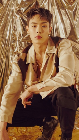 Shownu from Monsta X posing against a gold background