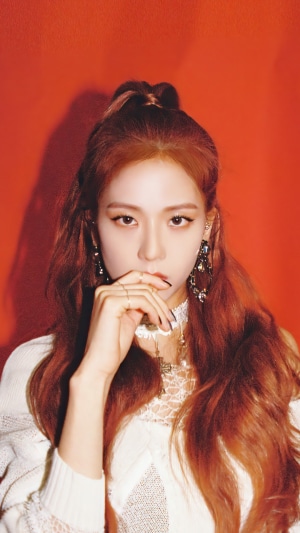 Jisoo from BLACKPINK posing against an orange background