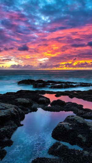 Sunset over the ocean with rocky coast and tide pools