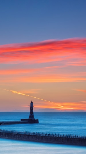 Lighthouse on a pier during a colorful sunset over the sea