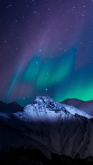 Aurora Borealis over snow-capped mountains at night