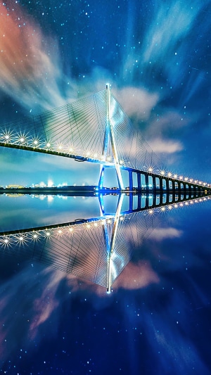 Cable-stayed bridge at night with starry sky reflection