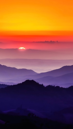 Sunset over layered mountains with orange sky