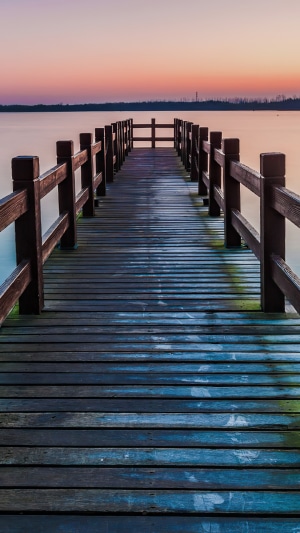 Wooden pier extending over calm water at sunset