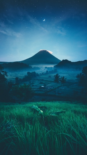 Volcano landscape at night with moon and stars