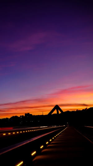 Road with lights at sunset with bridge silhouette