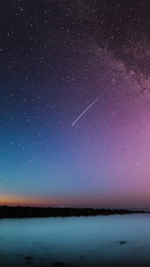 Night sky with milky way and shooting star over sea