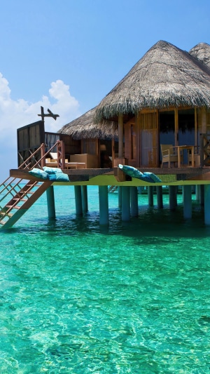 Overwater bungalow in turquoise ocean under blue sky