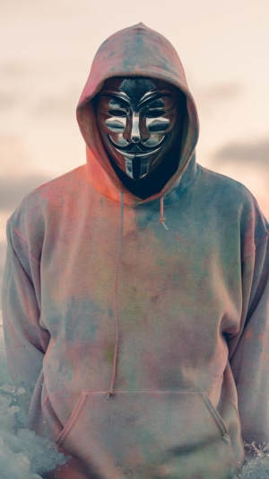 Person wearing Anonymous mask and tie-dye hoodie