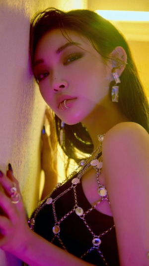 Chungha leaning against a wall with dramatic lighting