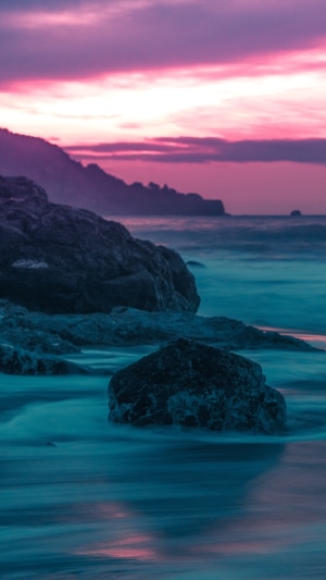 Ocean waves crashing on rocks at sunset