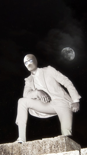 Moon Knight in a suit on a rooftop at night